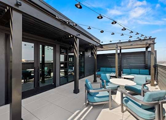 A patio with blue chairs and a table at Hawkins Press Apartments, Charlotte, North Carolina
