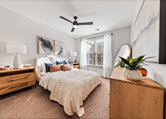 A bedroom with a bed, dresser, and ceiling fan.