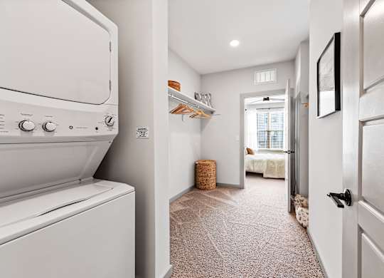 A white washing machine is in a narrow hallway.