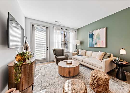 A living room with a white sofa, a wooden coffee table, and a TV on the wall.