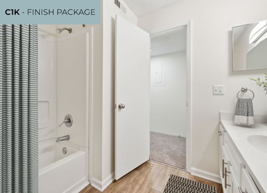 A bathroom with a white tub, sink, and shower curtain.