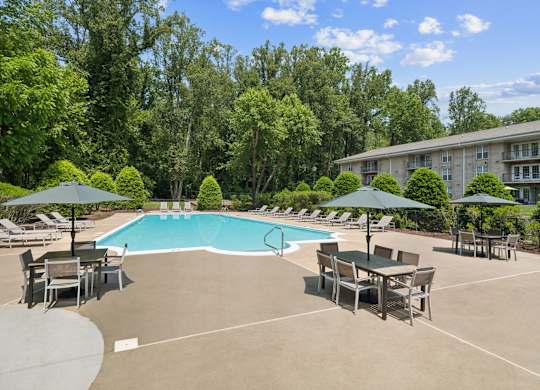 A large outdoor swimming pool surrounded by trees and lounge chairs at The Overlook at Quantico Apartments, Triangle, VA, 22172