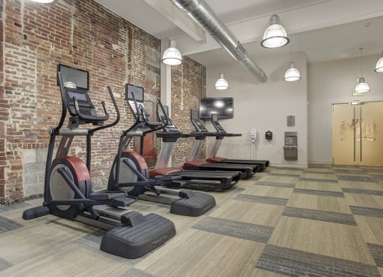 a row of treadmills in a gym with a brick wall at The Gunther, Baltimore, MD, 21224