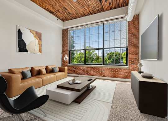 A living room with a brown leather couch, a black chair, a wooden coffee table, and a flat screen TV mounted on the wall.