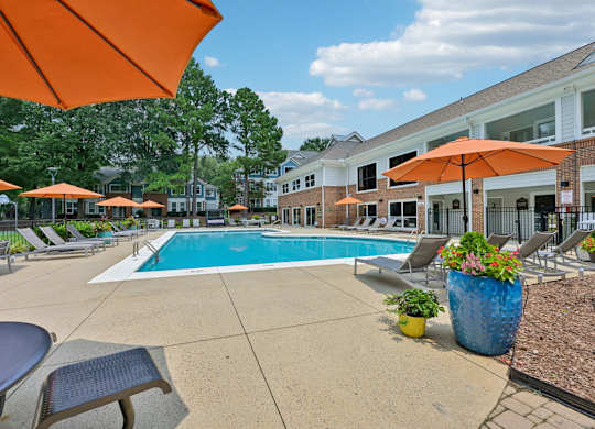 A pool surrounded by orange umbrellas and chairs.