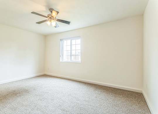A room with a ceiling fan and a window.