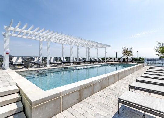a swimming pool with lounge chairs and a white canopy over it at 1405 Point Street Apartments in Baltimore, MD