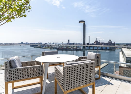 a patio with chairs and a table overlooking a river and a city at 1405 Point Street Apartments in Baltimore, MD