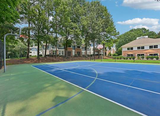 A blue and green tennis court surrounded by trees and buildings.
