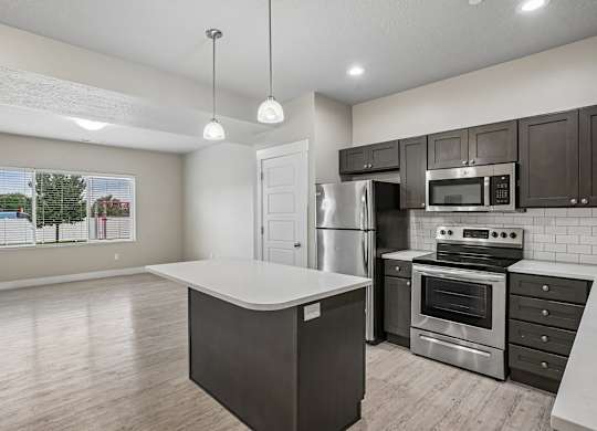 A kitchen with a white island and stainless steel appliances.