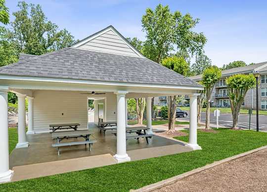 A white gazebo with a grey roof is surrounded by white columns and has picnic tables underneath at The Overlook at Quantico Apartments, Triangle, VA, 22172