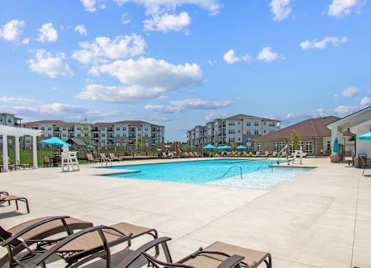 A large swimming pool surrounded by lounge chairs and umbrellas.