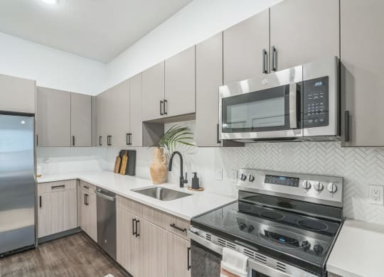 an apartment kitchen with stainless steel appliances and white cabinets  at La Unión, Tampa, FL