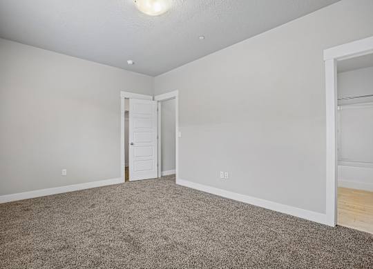 A room with a carpeted floor and a doorway leading to another room.