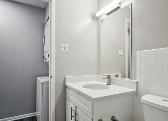 A white bathroom with a sink, mirror, and toilet at Shenandoah Station Apartments, Triangle