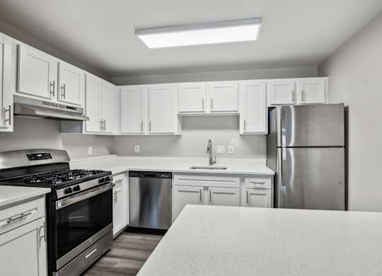 A kitchen with white cabinets and a stainless steel refrigerator at Shenandoah Station Apartments, Triangle, VA