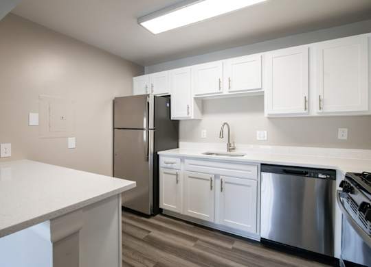A kitchen with white cabinets and a stainless steel refrigerator at Shenandoah Station Apartments, Virginia