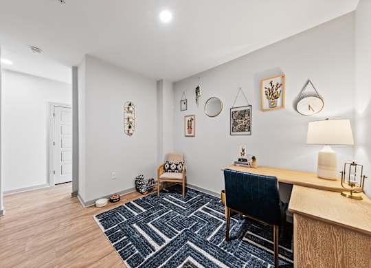 A room with a blue chair and a desk with a lamp on it.