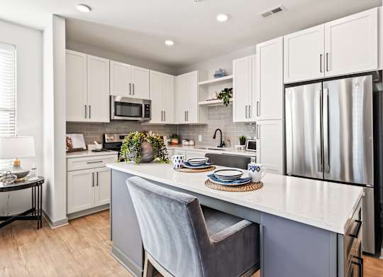 A kitchen with a white countertop and a grey chair.