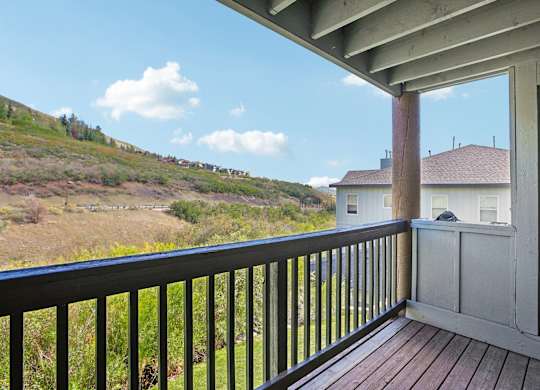 A balcony with a black railing overlooks a grassy hillside.