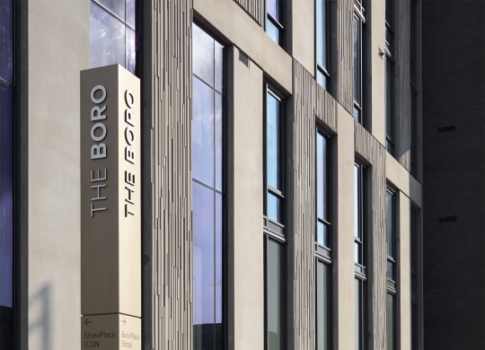 a person sitting on a bench in front of a building at The Boro, Tysons, 22102