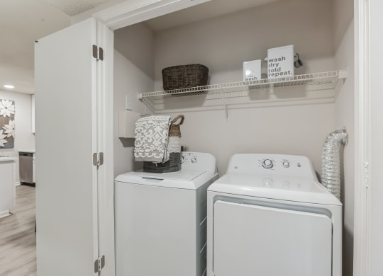 a white washer and dryer in a laundry room with a shelf above it at St. Andrews Reserve, Wilmington, NC