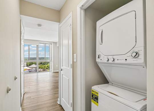 A white dryer is sitting in a laundry room next to a door.