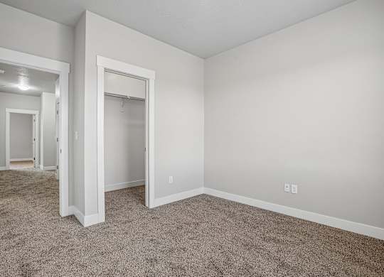 A large, empty room with carpeted flooring and white walls.