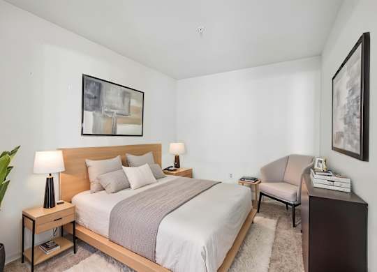 A bedroom with a large bed and a chair.