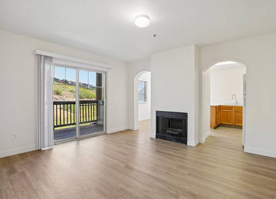 A large, empty room with a fireplace and sliding glass doors.