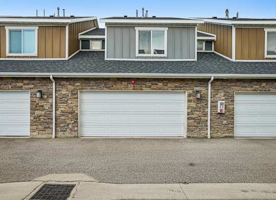 A house with a stone wall and three garage doors.