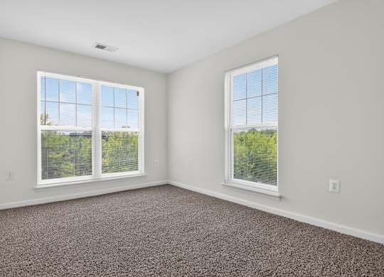 A room with two windows and carpeted floor.