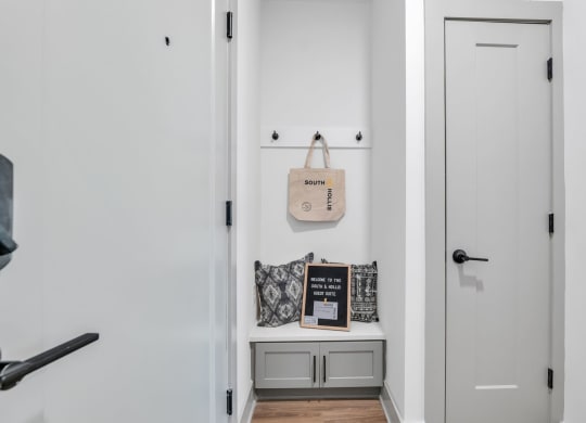 a white hallway with a white door and a white shelf with a bag on it