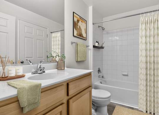 A bathroom with a white toilet, a sink with a green towel on it, and a shower with a white curtain.