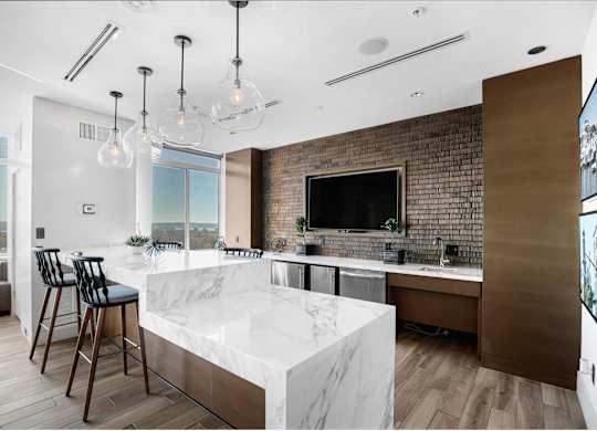 A modern kitchen with a marble countertop and a brick accent wall.