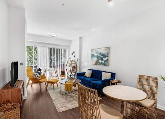 A living room with a blue couch and wooden furniture.