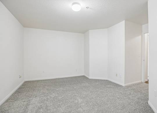 A large empty room with carpeted floor and white walls.