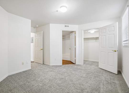 A spacious, empty room with white walls and carpeted floor.