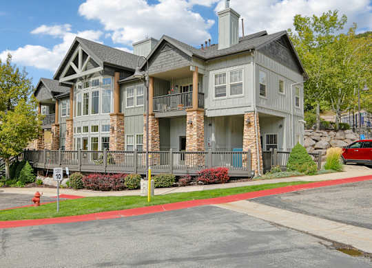 A large two-story house with a grey and brown exterior and a red fire hydrant in front.
