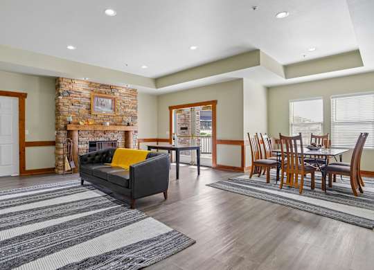 A living room with a stone fireplace and a grey couch.