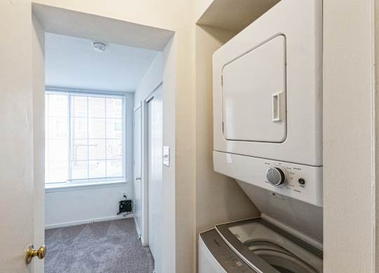A small, clean, and modern kitchen with a washing machine and dryer built into the cabinetry.