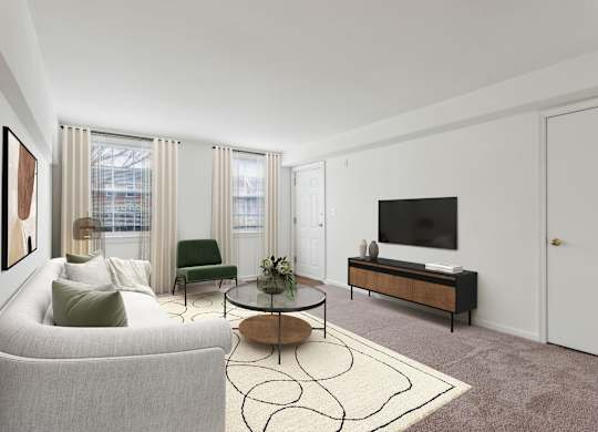 A living room with a grey couch, a green chair, a coffee table, and a television at The Fields of Bethesda, Chevy Chase, MD