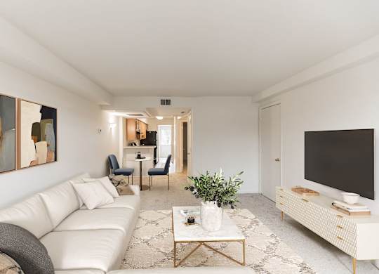 A living room with a white couch, a coffee table, and a television at The Fields of Rockville, Rockville, 20850