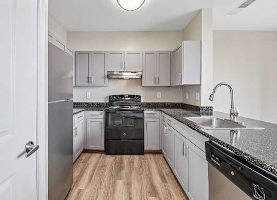 A kitchen with a black dishwasher and stove top oven.