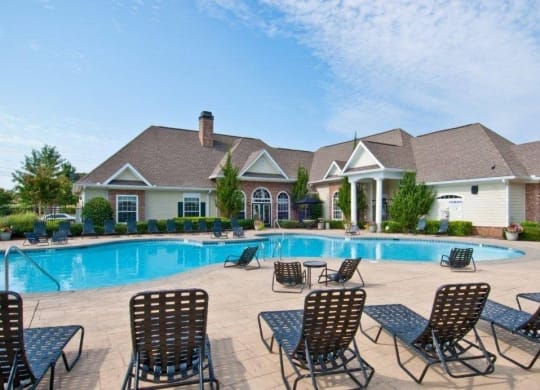 a swimming pool with chairs around it in front of a house at Alexander Ridge Apartments, Canton , Georgia