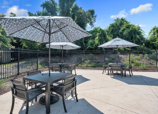 a patio with tables and umbrellas and a fence at St. Andrews Reserve, Wilmington, North Carolina