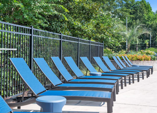 a row of blue lounge chairs in front of a black fence at St. Andrews Reserve, North Carolina, 28412
