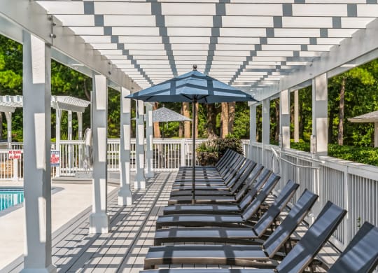 a row of lounge chairs under a white covered pavilion with an umbrella at St. Andrews Reserve, Wilmington, NC, 28412