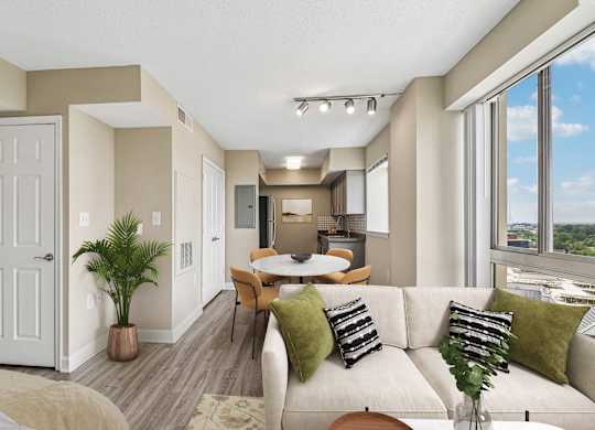 A well-lit living room with a couch, chairs, and a dining table.
