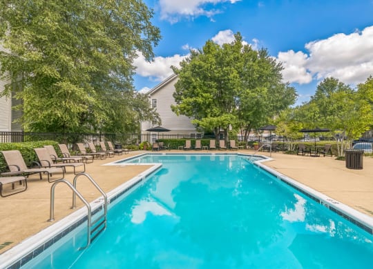 a swimming pool with chairs and trees and a building in the background at Sanger Place, Virginia, 22079